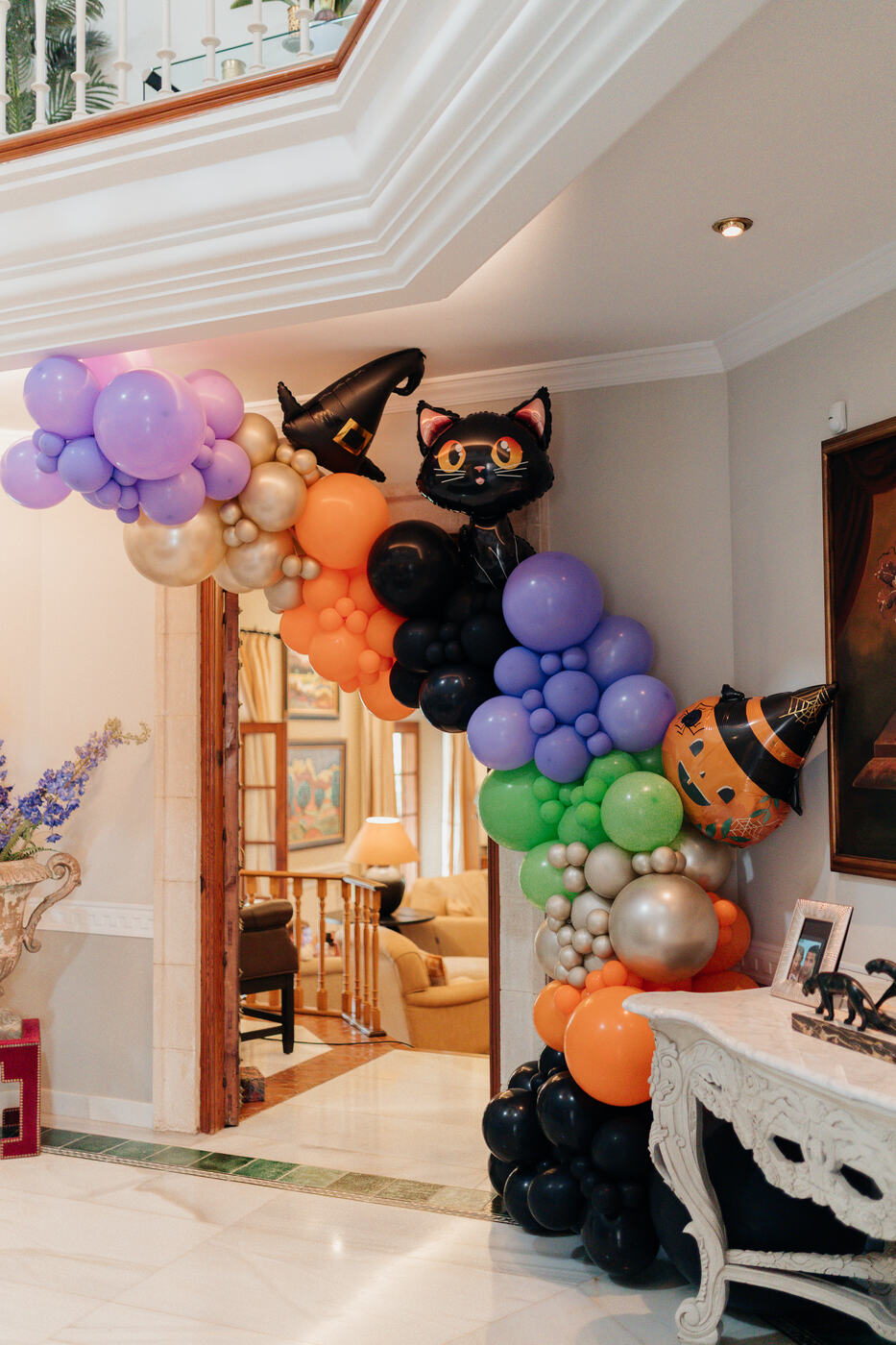 Halloween balloon garland with a black cat, witch hat and pumpkin foil balloons framing a villa doorway, Marbella