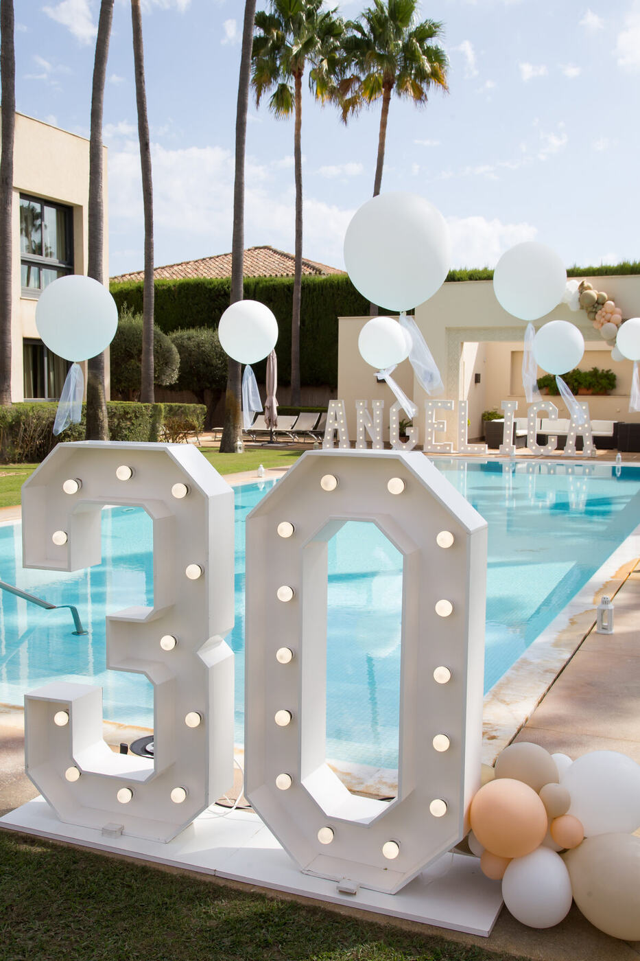 Giant light-up 30 birthday numbers with round balloons beside a pool, Marbella