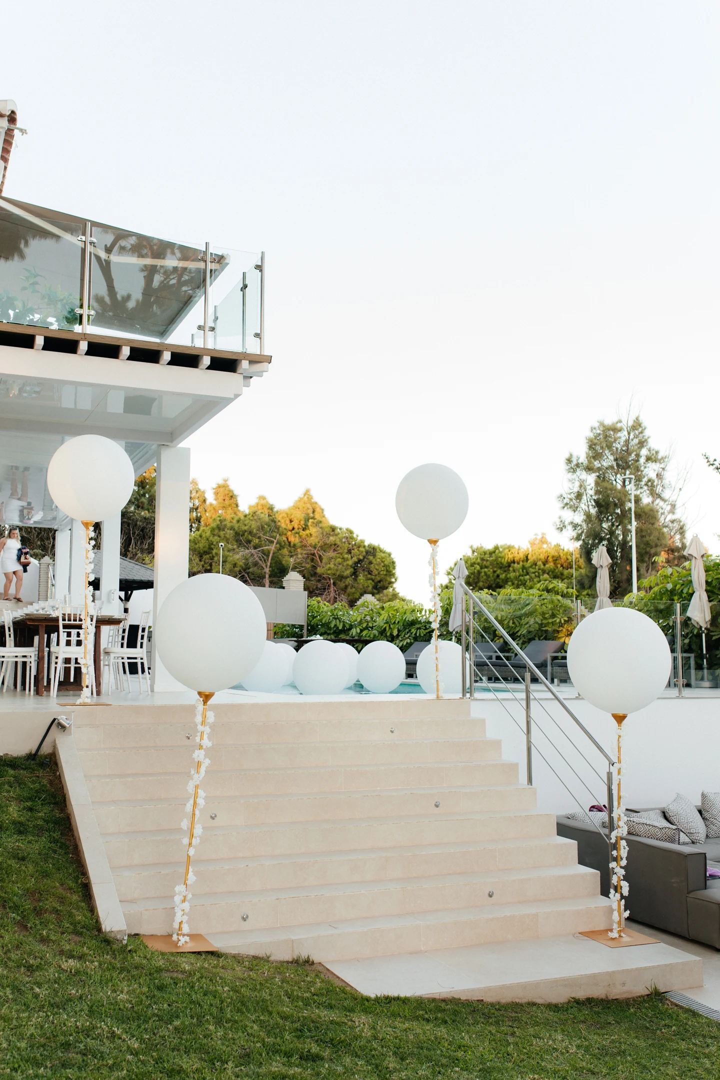 Giant white balloons on flower-wrapped stands lining a villa entrance in Mijas