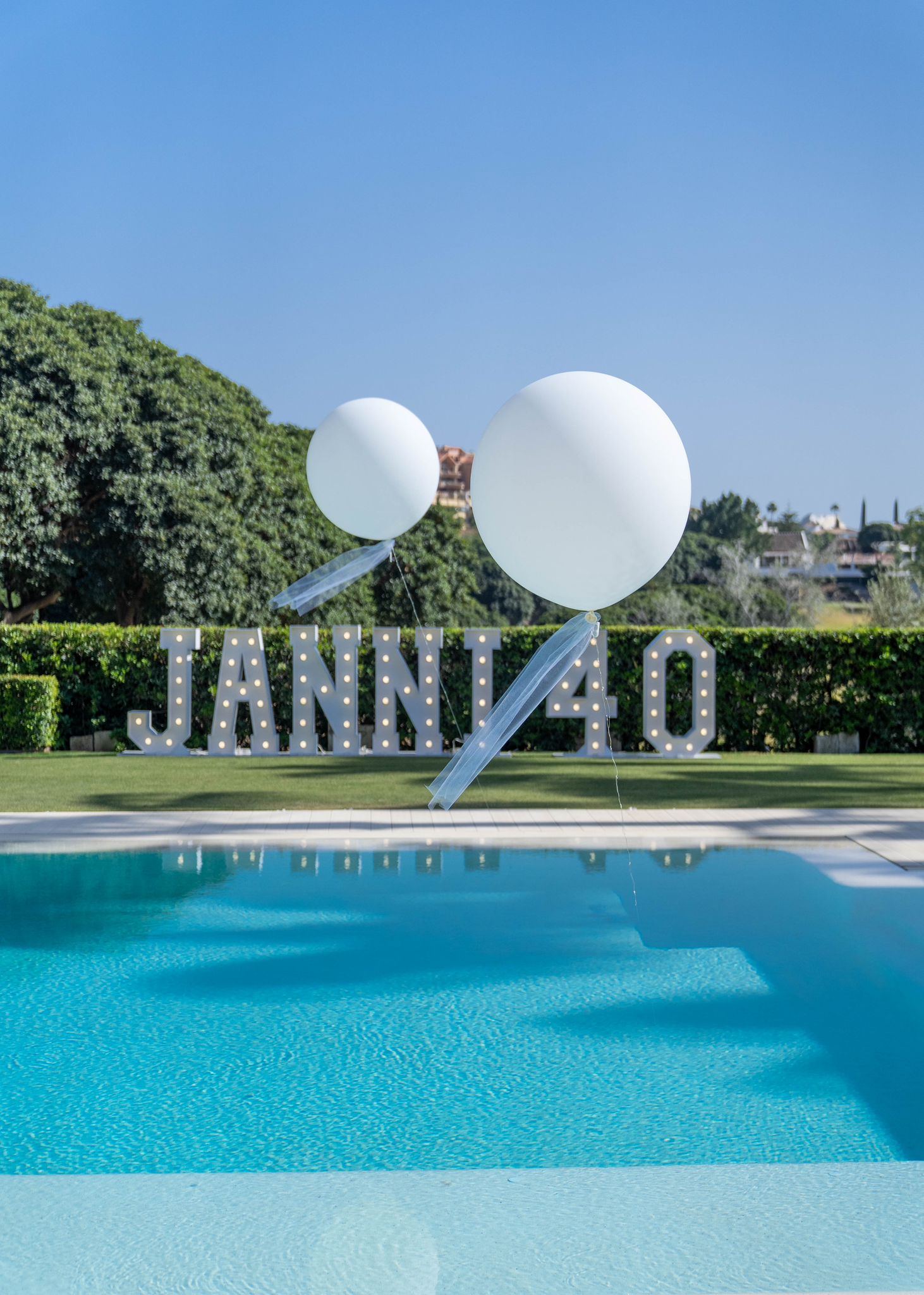 Giant light-up 40 birthday numbers with round balloons beside a pool, Marbella